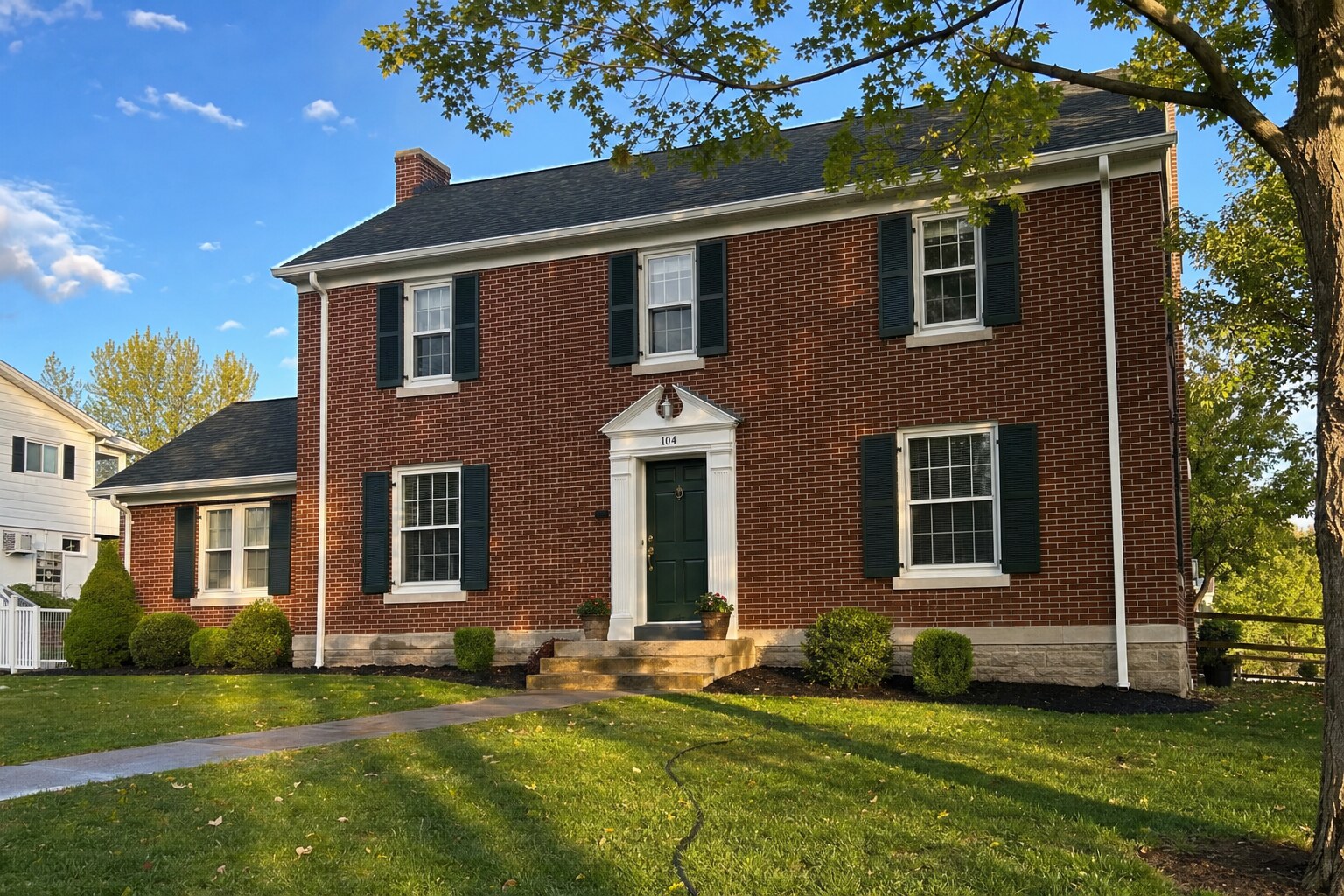 Two-story Federal-style red-brick home, freshly soft-washed in golden-hour light