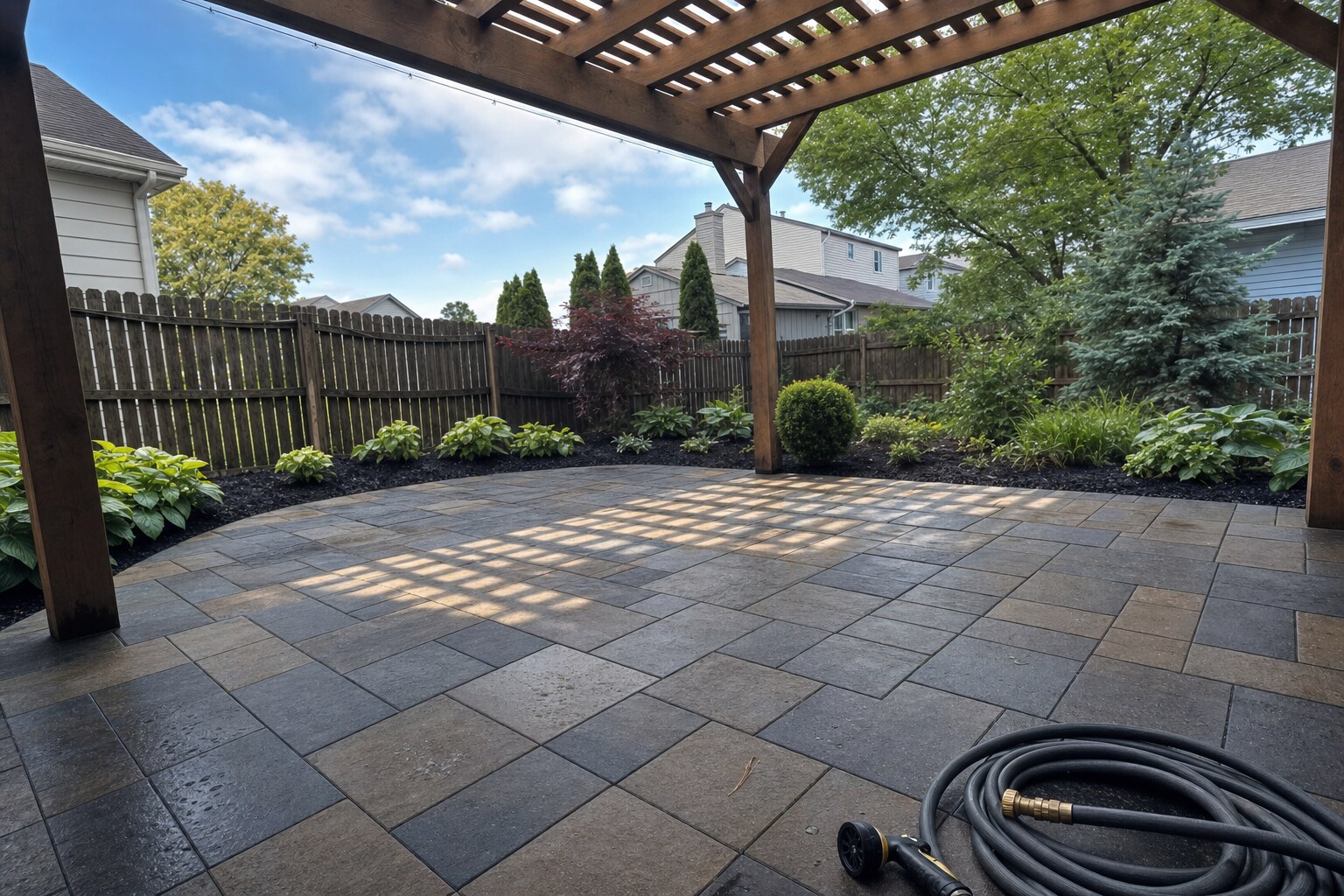 Charcoal-and-tan flagstone paver patio under pergola, freshly cleaned
